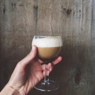 woman's hand holding glass of irish coffee drink