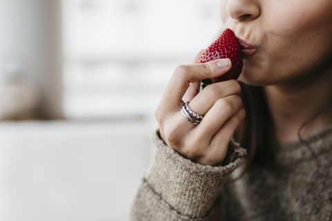 Womans hand holding strawberry, close-up