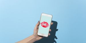 woman's hand shows her smartphone with lipstick kiss