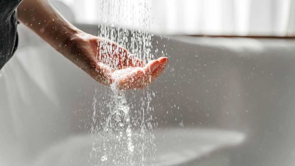 a woman's hand touches the water running from the shower