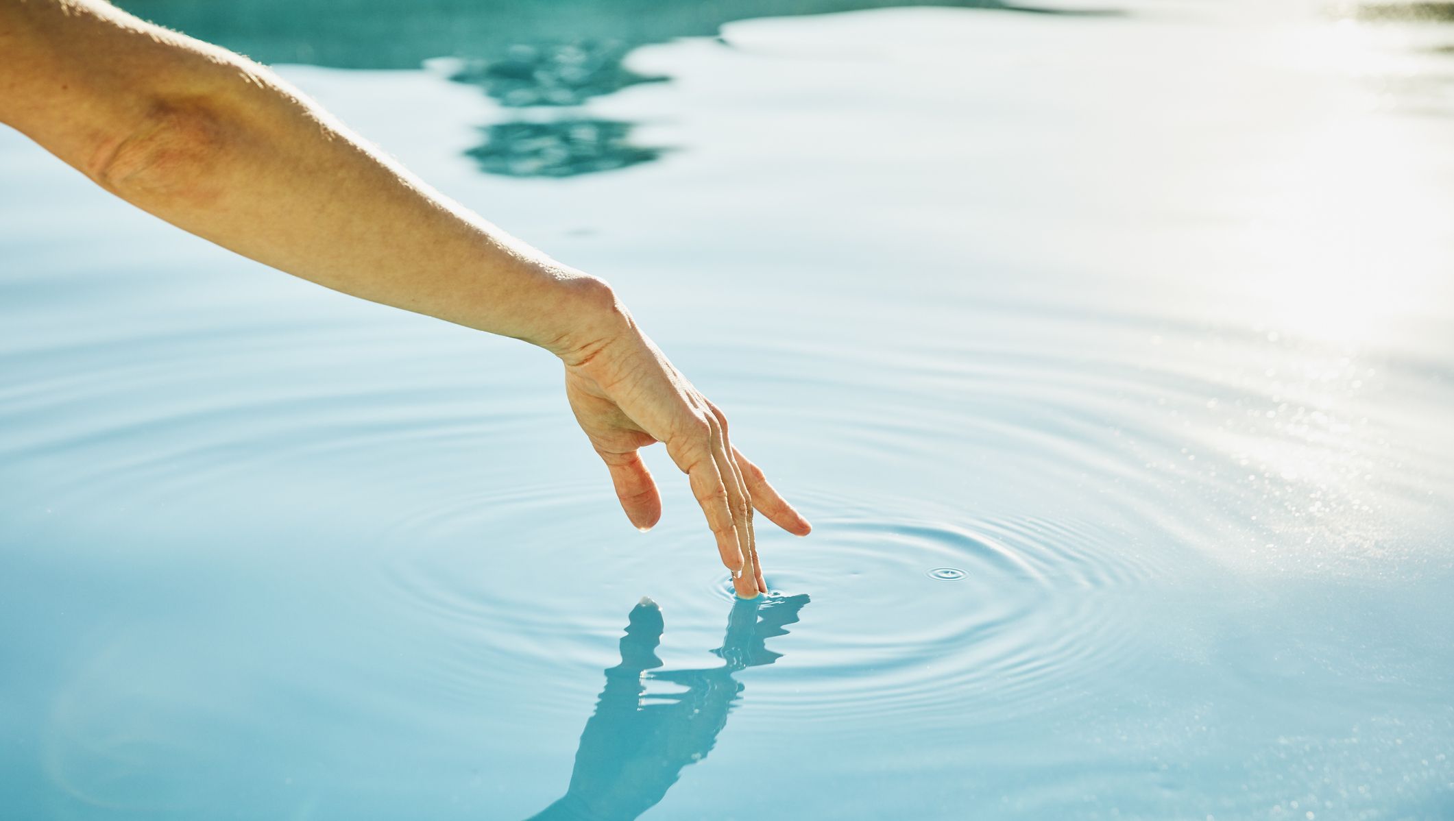womans hand touching surface of water