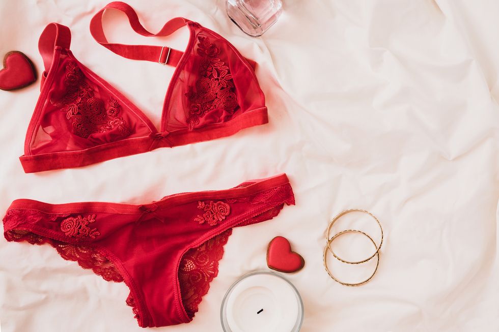 woman's lingerie on white bed sheets flatlay