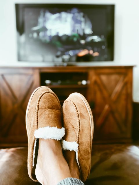woman's slippered feet on ottoman in front of tv