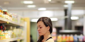women choosing a dairy products at supermarket reading product information