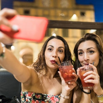 Women drinking cocktails taking selfie with smartphone