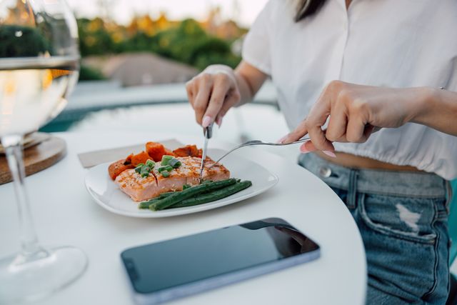 women eating a grilled salmon in a restaurant