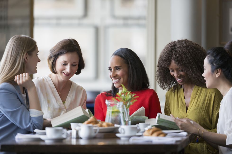 Women friends discussing book club book at restaurant table