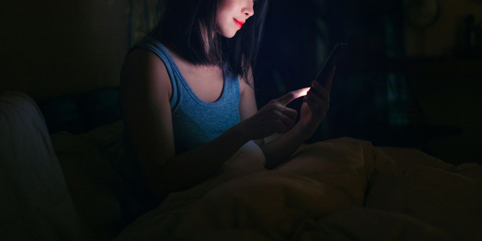 a woman looking at her phone in bed at night