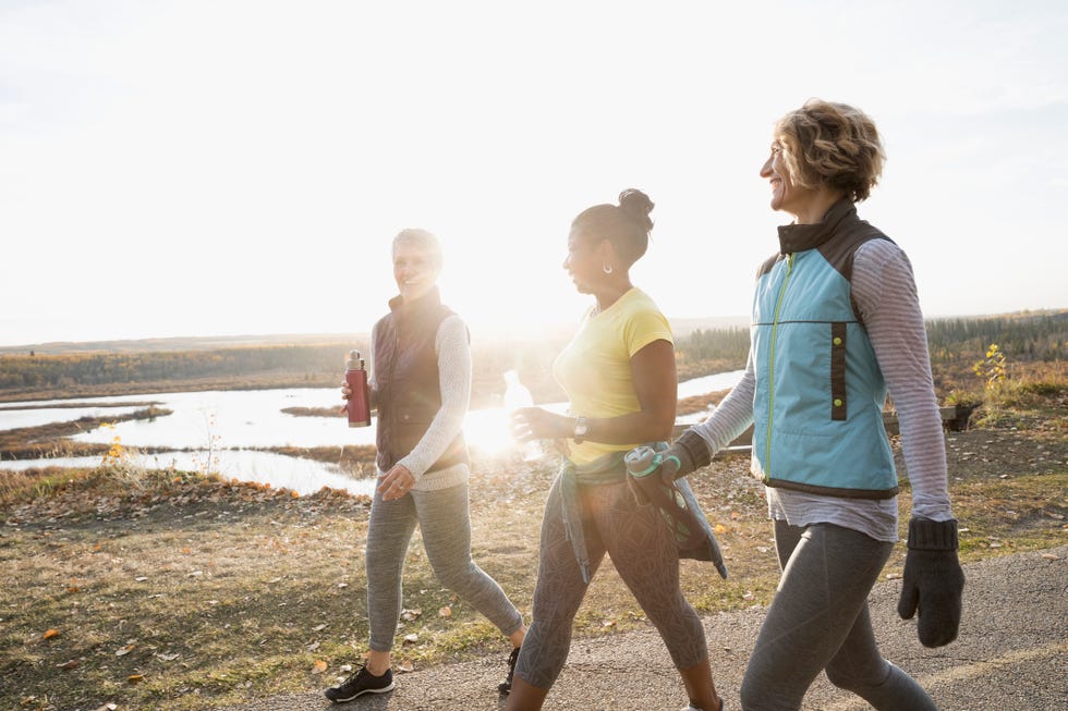 Women walking exercising on sunny path in autumn park