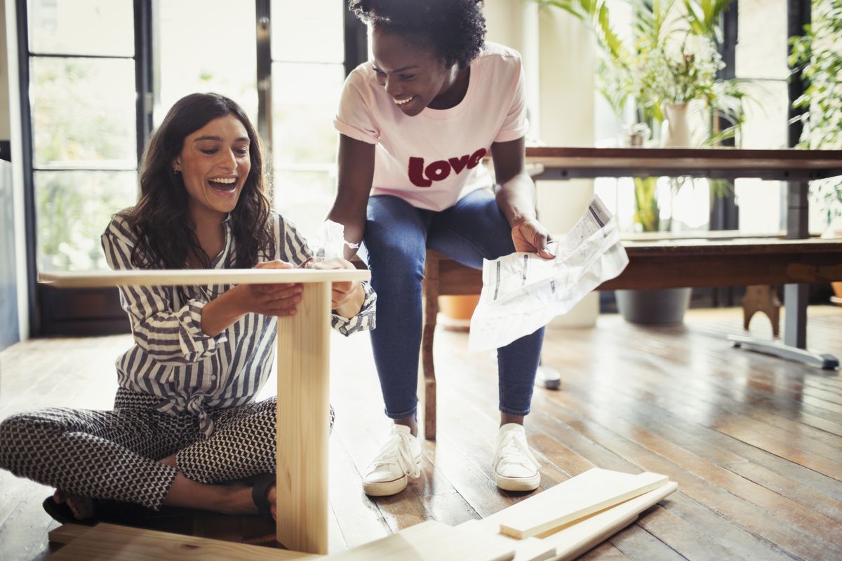 Women with instructions assembling furniture