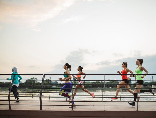 group of women jogging along a waterfront pathway