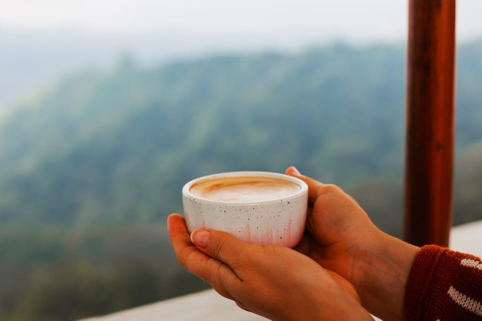 women's hands hold a round cup of coffee