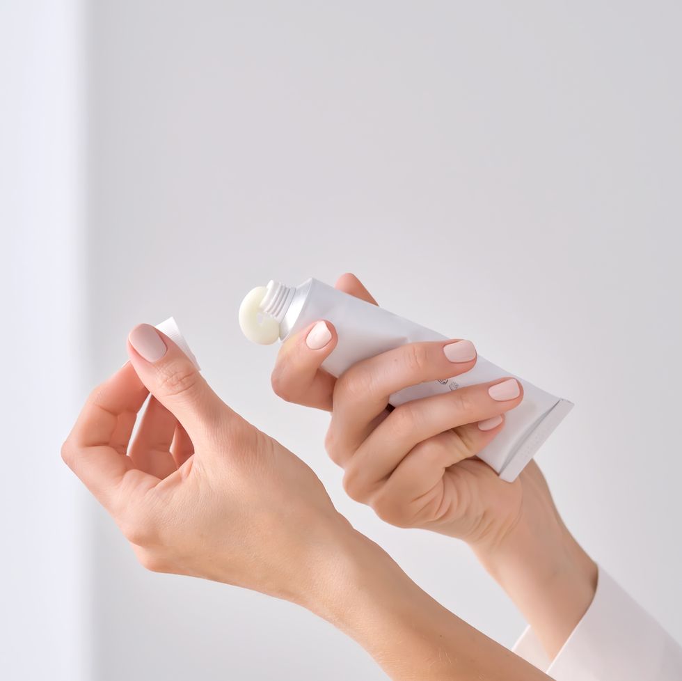 women's hands with a white tube of cream