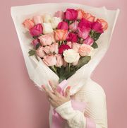 women's holding a big bouquet of roses on pink background