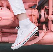 woman in white sneakers on pink painted motorcycle