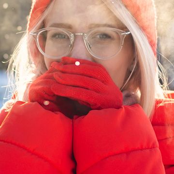 woman warming hands in red winter gloves