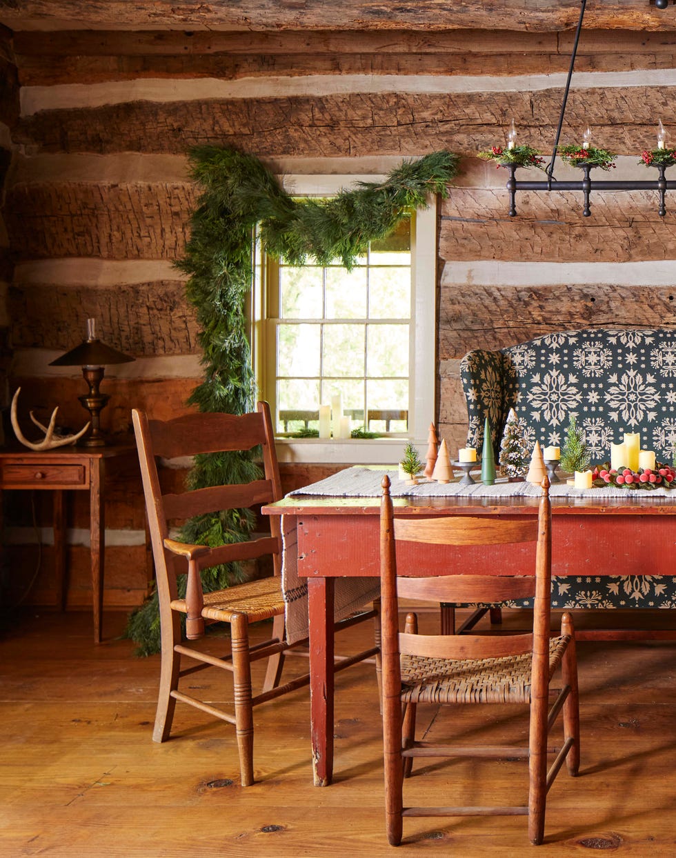 winter dining table in a cabin with askew greenery hung from a nearby window