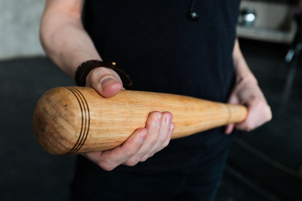 a wooden baseball bat in the hands of a man or a teenage boy, a student the concept of sports play and leisure, entertainment and competitions, self defense, defense and protection