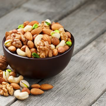 wooden bowl with mixed nuts on a wooden gray background