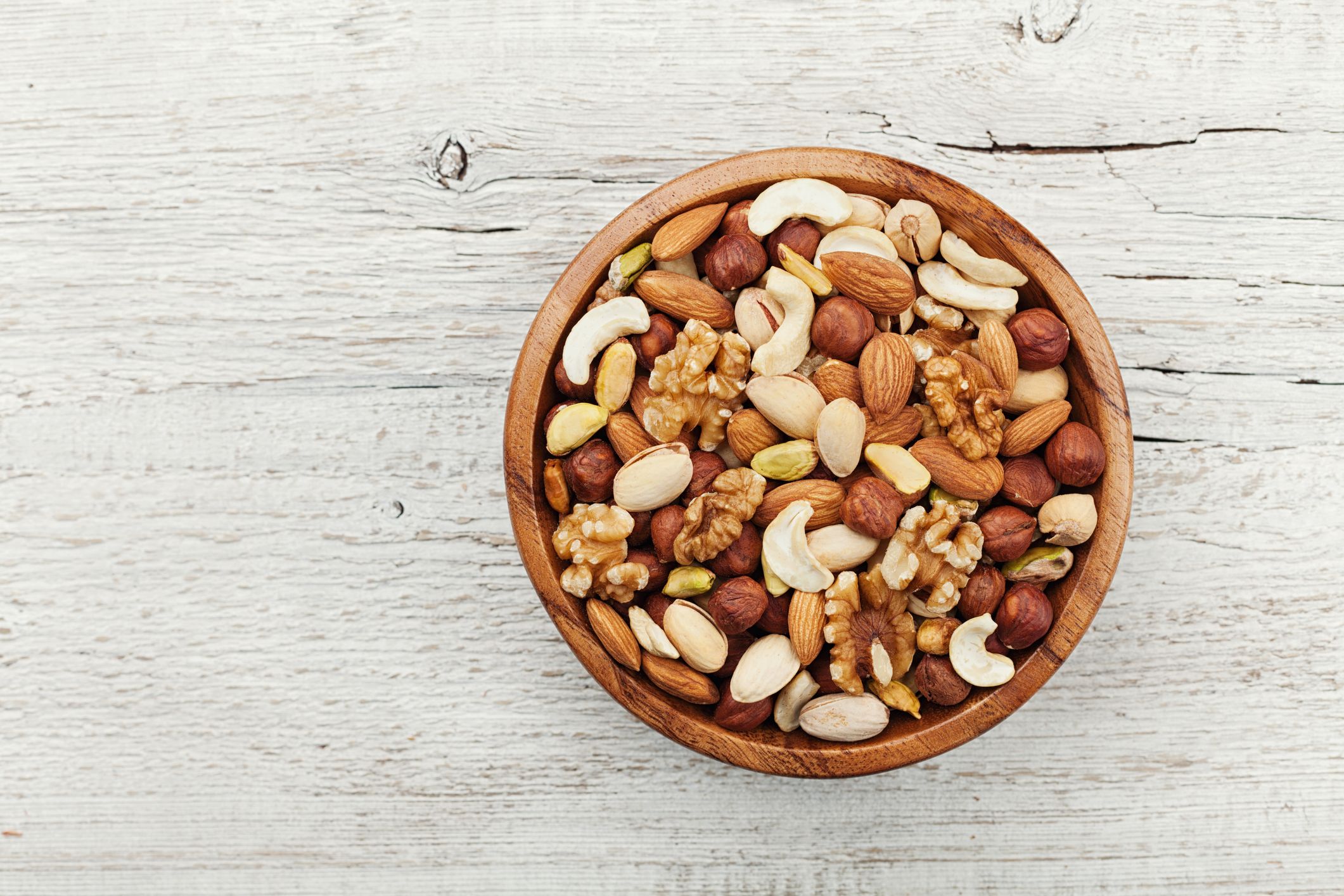 Wooden bowl with nuts. Walnut, pistachios, almonds, hazelnuts. Flat lay.