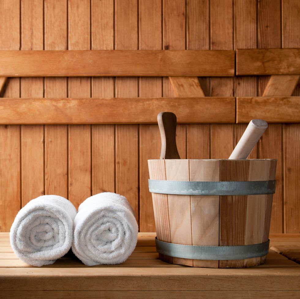 wooden bucket and white rolled towels in a sauna