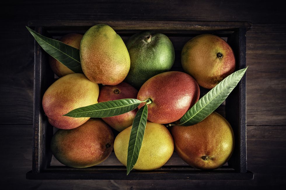 tropical fruits wooden crate with assorted mangos in rustic kitchen natural lighting
