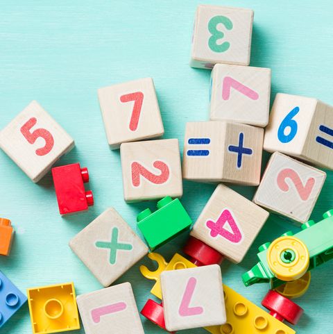 Wooden cubes with numbers and colorful toy bricks on a turquoise wooden background.