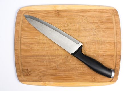 wooden cutting board with large knife across isolated on white