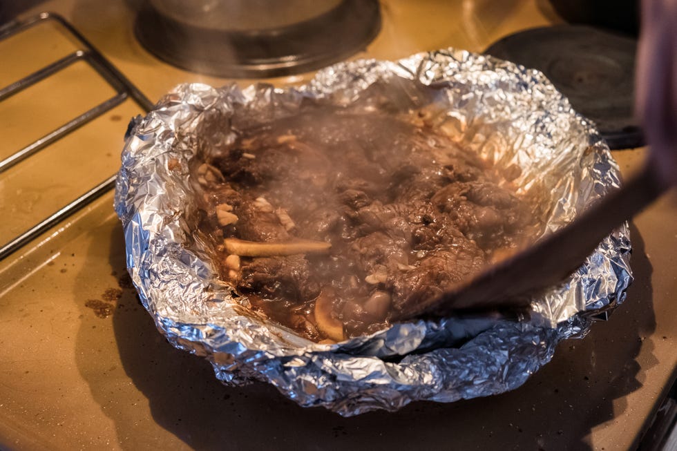Wooden flipper frying steak beef in foil