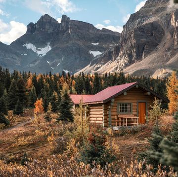 wooden huts with rocky mountains in autumn forest at assiniboine provincial park