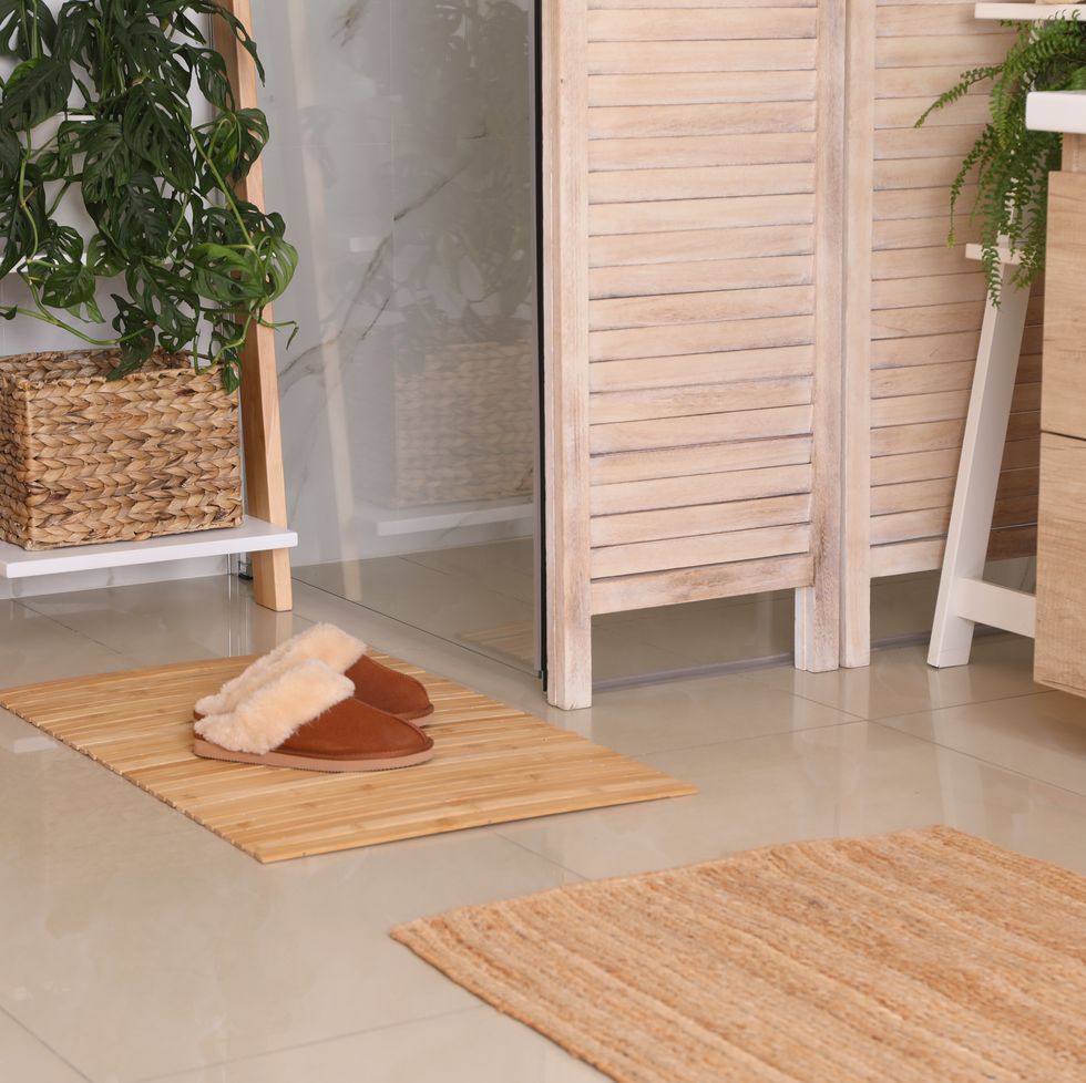 wooden mat and slippers on tiled floor in bathroom. stylish accessory
