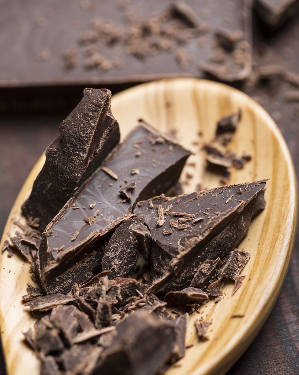 wooden spoon with aromatic dark chocolate shavings for baking on wooden background, close up