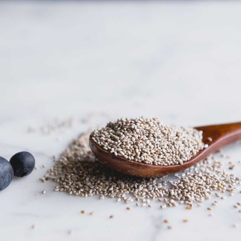 wooden spoon with chia seeds and blueberries on marble counter