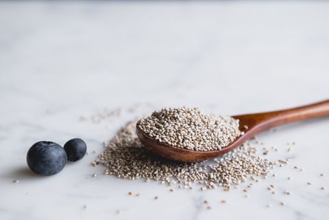 wooden spoon with chia seeds and blueberries on marble counter