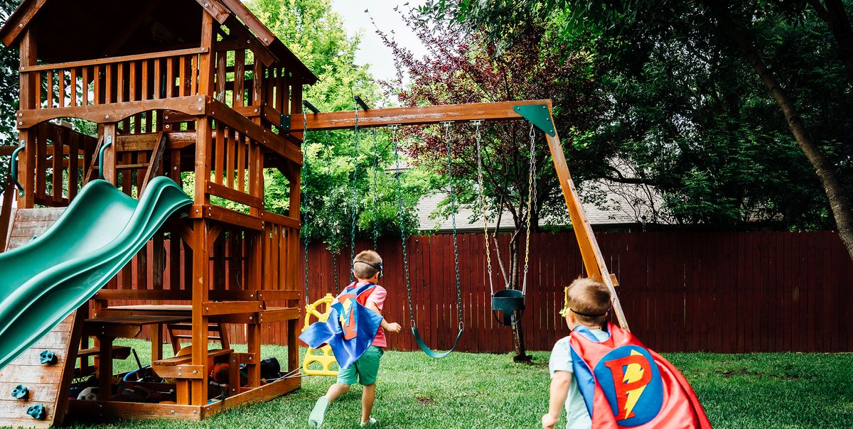 kids in superhero capes playing with wooden swing set
