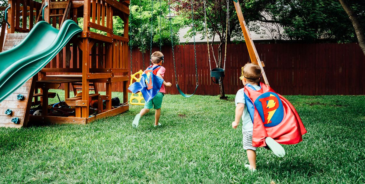kids in superhero capes playing with wooden swing set