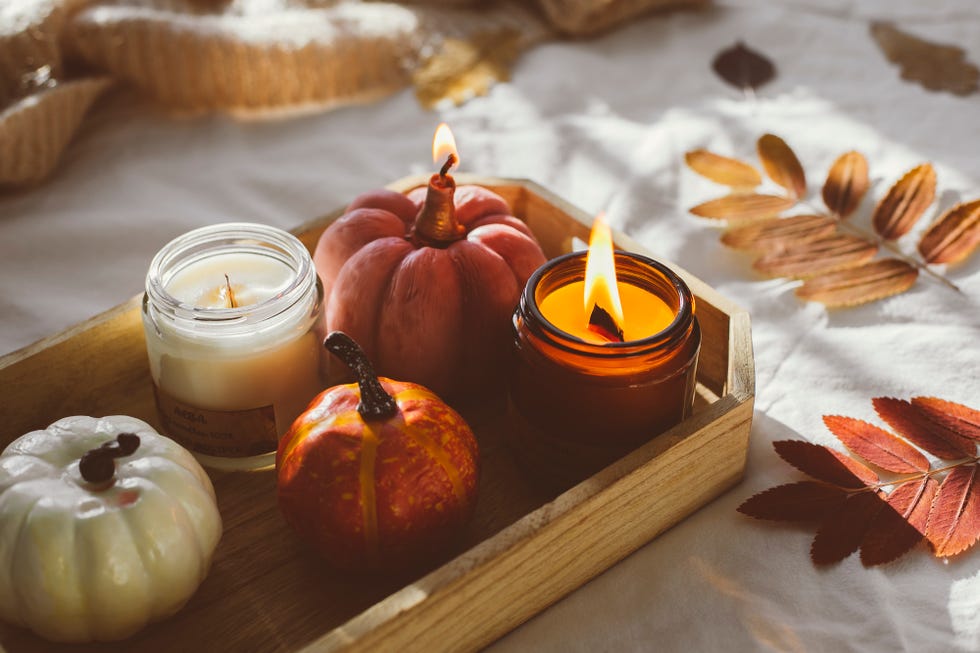 wooden tray with atmospheric candles and aututmn fall leaves on white bed
