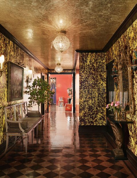 glimmering finishes greet guests in the foyer like an ebony diamond patterned floor and banana yellow tortoiseshell walls and the ceiling’s paper collage treatment on silver paint