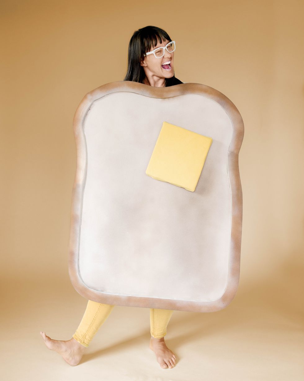 woman wearing a buttered toast costume made out of foam with a yellow pat of butter on it made out of foam and her head and legs peeking out