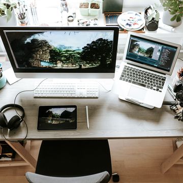 work from home desk with monitor laptop headphones and digital camera