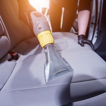 worker cleans car interior with vacuum cleaner