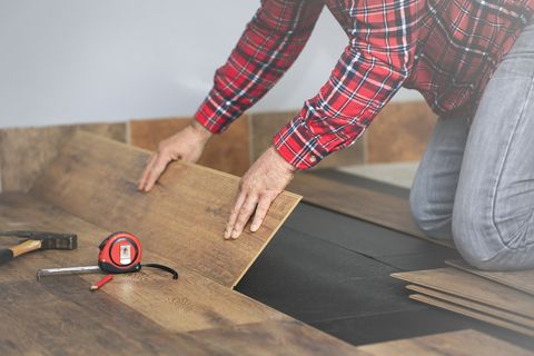 worker hands installing timber laminate floor in the room