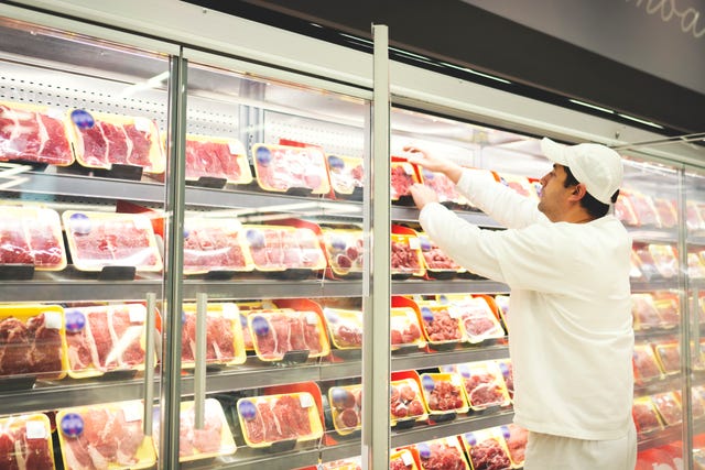 worker in a supermarket handling meat