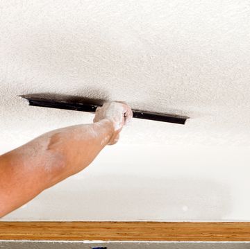 worker troweling drywall mud on a ceiling for knockdown texture