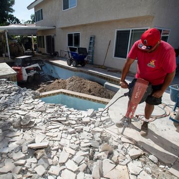 man in a red shirt working to install an inground pool