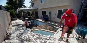 man in a red shirt working to install an inground pool