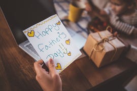working at home father holding father's day card and gift