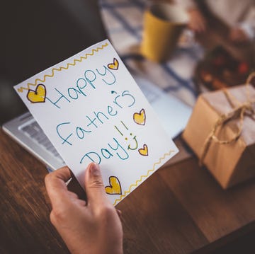 working at home father holding father's day card and gift