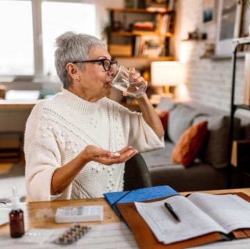 working senior woman taking pills from pill organizer