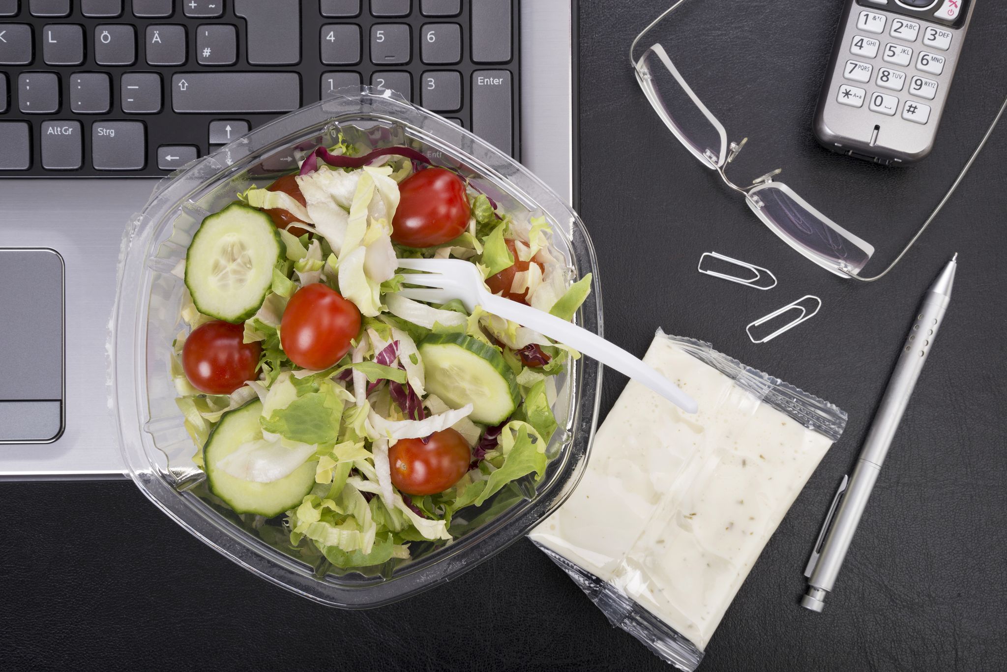 Workplace with mixed salad on laptop